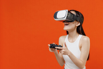 Fun young woman of Asian ethnicity 20s years old in white tank top watching in vr headset pc gadget...