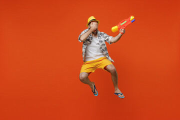Fototapeta na wymiar Full body young happy tourist man wear beach shirt hat hold in hand play shoot from water gun look camera isolated on plain orange background studio portrait. Summer vacation sea rest sun tan concept.