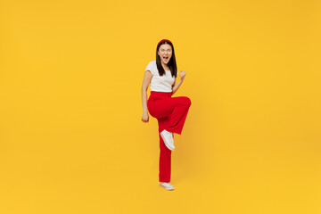 Fototapeta na wymiar Full size body length young girl woman of Asian ethnicity 20s years old wears casual clothes doing winner gesture celebrate clenching fists say yes isolated on plain yellow background studio portrait.