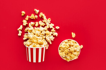 Two striped round box with popcorn on a bright red background. Top view, copy space