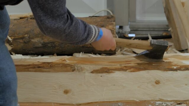 Man lumberjack cutting large log with axe - wood shavings, chips flying in slow motion at workshop - close up. Craftsmanship, revival and handwork concept