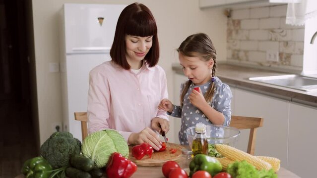 Caucasian mother teach little preschooler daughter chop pepper preparing salad for lunch together, loving mom and small girl child cooking dinner together, kid helping mommy with food preparation