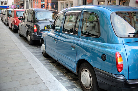A line of taxis parked on a city road waiting for passengers, UK.
