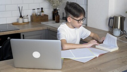 A boy with glasses is doing his homework. Study
