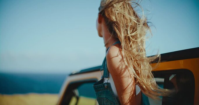 Beautiful young blond woman relaxing and enjoying the wind in her hair on epic summer road trip