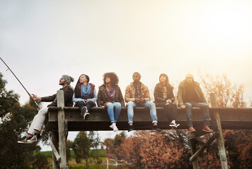 Collect moments, not things. Shot of a group of friends sitting on a pier together on a weekend breakaway. - Powered by Adobe