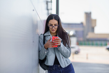 A beautiful young woman in the parking lot who uses the phone while checking the mail and writing messages.