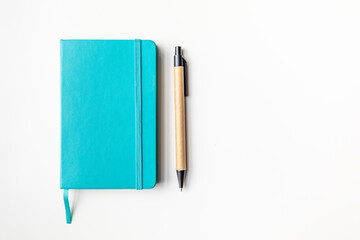 Turquoise notebook and cardboard pen on a white background.