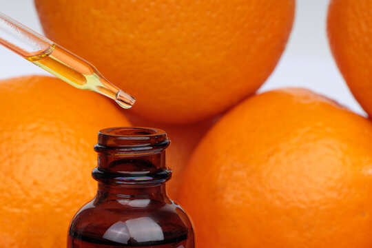 Essential oil with oranges. Pipette with orange essential oil over bottle and oranges. Natural medicine concept.