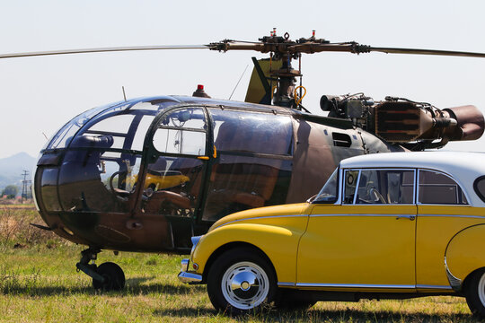 Light Military Helicopter With Yellow Classic Car