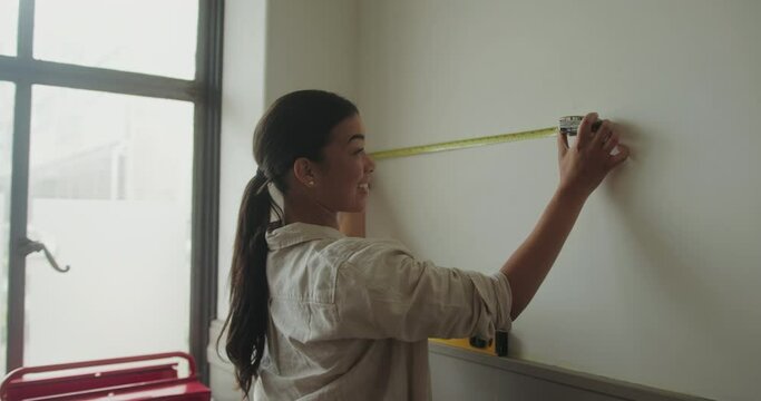 Mid Adult Female Measuring Wall for Home Renovations