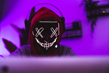 Masked hacker in action. Safety in the internet concept. Magenta color. High quality photo