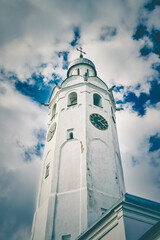 Fototapeta na wymiar The old clock tower Chasozvonya in the Kremlin of Veliky Novgorod against the cloudy blue sky