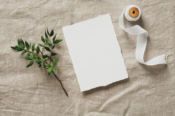 Wedding invitation design. Blank paper card template, green branch, silk ribbon on linen...