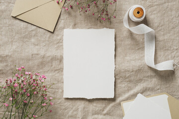 Wedding flat lay composition with blank paper card mockup, silk ribbon, envelopes, gypsophila...