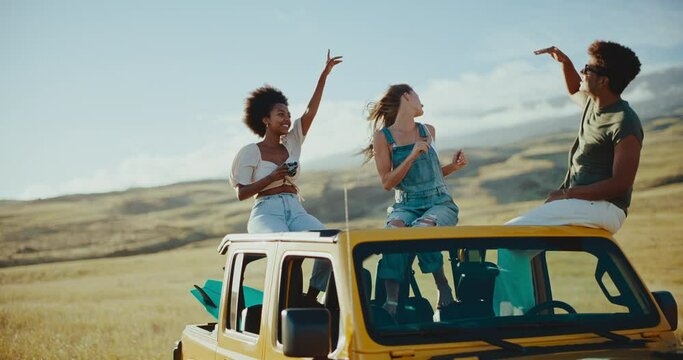 Three best friends dancing and laughing on the roof of their car on summer road trip, travel and adventure lifestyle