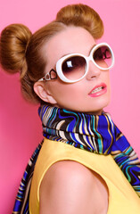 Portrait of cute attractive blonde young woman in sunglasses and blue neckerchief on pink background