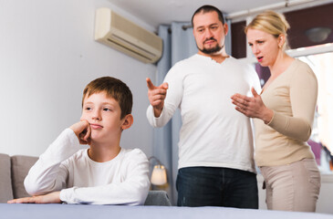 Obraz premium Frustrated boy sitting at home while parents berating him