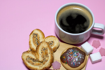 A cup of black coffee and cookies with marmalade candies on a pink background.