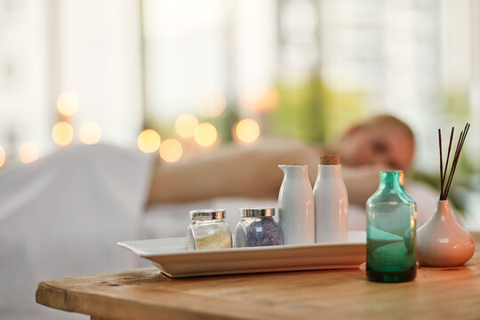 Are you ready to soak up some well-deserved pampering. Cropped shot of various pampering essentials in a spa with a young woman in the background.