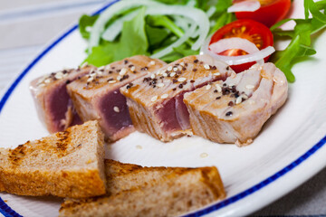 Fototapeta na wymiar Tataki (tuna fillet) served with toasts and greens on plate