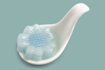 Thai sweet layered cake, called kanom chan, is an traditional Thai dessert, colorful layers in flower shape on white spoon on blue background. Clipping path