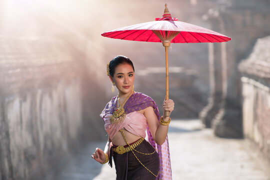 woman with umbrella. Thai Woman in Traditional Costume of Thailand. Beautiful Thai girl in traditional dress costume in Choeng Tha as Thai temple where is the public place, Ayutthaya province
