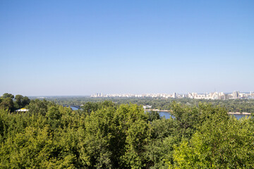 Panorama of Kyiv, in Ukraine, with a view over the Dnipro, or Dnieper river and the city center, in front of a green forest of trees, in Kiev, capital of Ukraine. ..