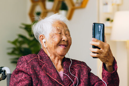 Asian old senior making video call via mobile phone talking with family