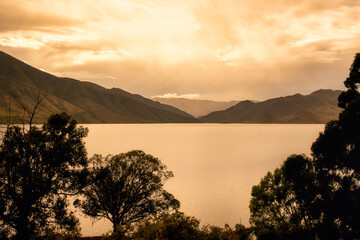 Eerie atmosphere in the early morning looking across a very calm Lake Benmore in moody rainy weather