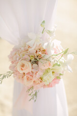 Colorful pink and light green floral arrangement tied to an arch in a wedding ceremony