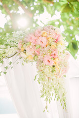 Colorful pink and light green floral arrangement tied to an arch in a wedding ceremony
