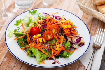 Fresh mixed salad with lettuce, corn, olives and cherry tomatoes at plate