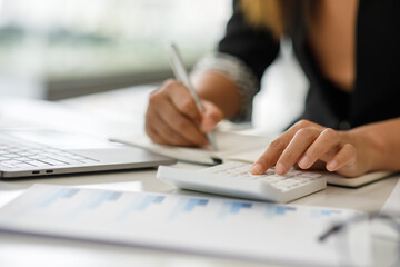 Fototapeta premium businesswoman working on desk office with using a calculator to calculate the numbers, finance accounting concept