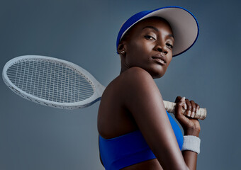 Get up and make it happen. Studio shot of a sporty young woman posing with a tennis racket against a grey background. - obrazy, fototapety, plakaty