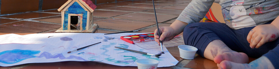 Criança sentada, pintando com aquarela