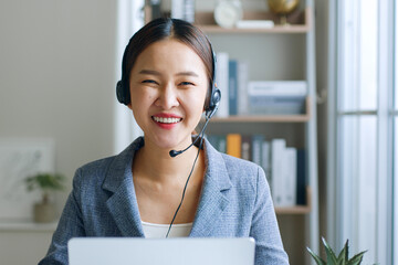 Young Asian businesswoman, call center, customer service wearing headphone and smiling. Look at...