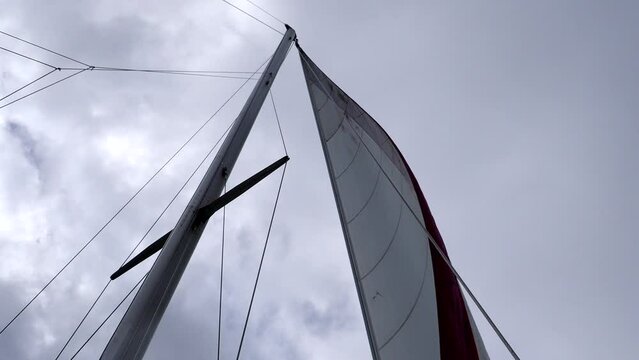 Sails and rigging blowing in the wind on boat with cloudy sky
