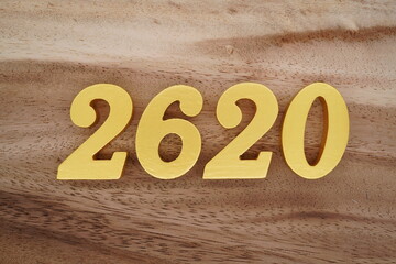 Golden Arabic numerals on a real brown and white wooden floor number 2620