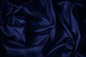 Navy blue silk satin. Beautiful wavy folds. Dark elegant background with space for design. The...