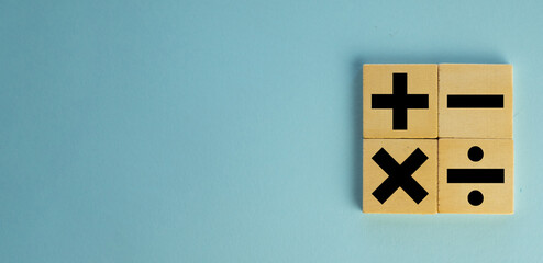 mathematic concept.,Black color of mathematical operations or Plus, minus, multiply, divide symbols on wooden cube over blue pastel background with copyspace for put text or logo.