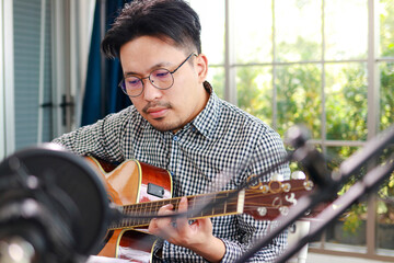 Asian musician artist Sit and play guitar in the studio. Music concept. online music lessons