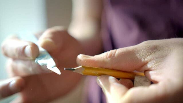 Marco picture of hand sharpening blunt pencil with art knife and cutting mat on background