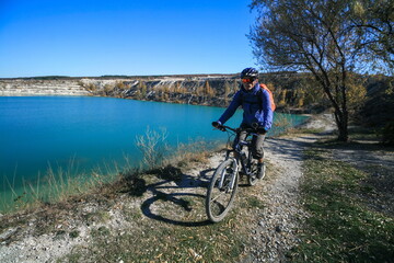 A cyclist rides along the shore of a mountain lake, Crimea.