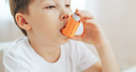 Fototapeta premium Little boy inhales medicine through an asthma inhaler.