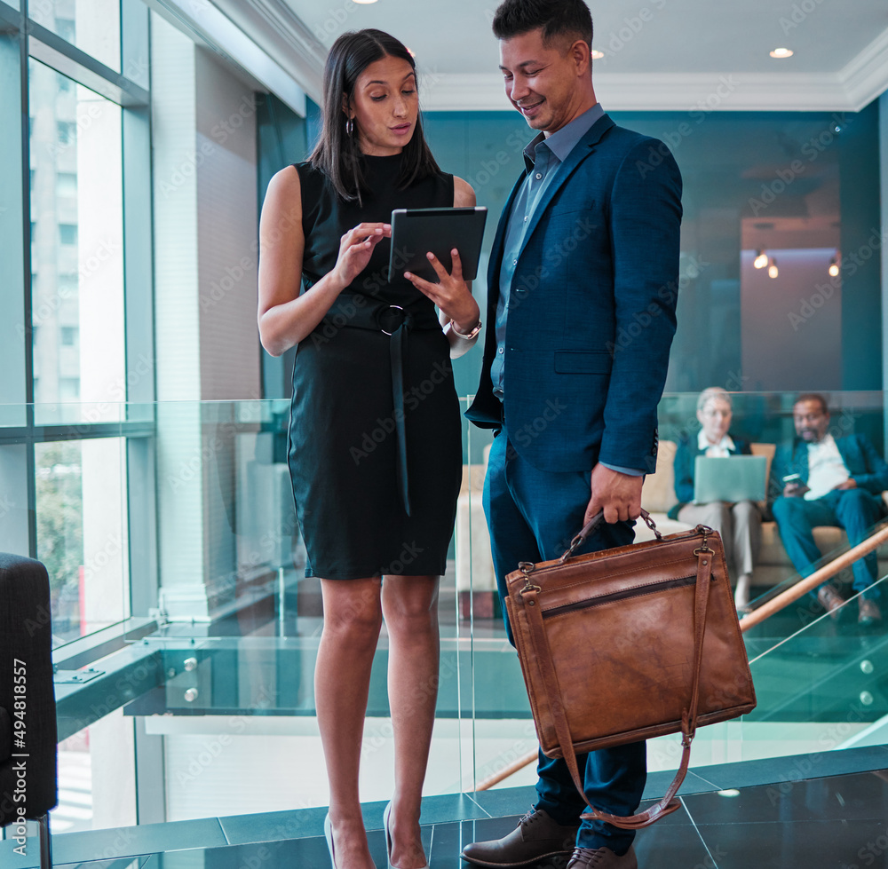 Poster i need to discuss this with you. shot of two young businesspeople using a digital tablet at work.