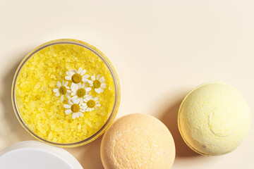 Top view bath bombs and sea salt with  herbal extract of chamomile, spa products close up. Natural cosmetic for beauty treatment and body care, home care, herbal medicine, beige background