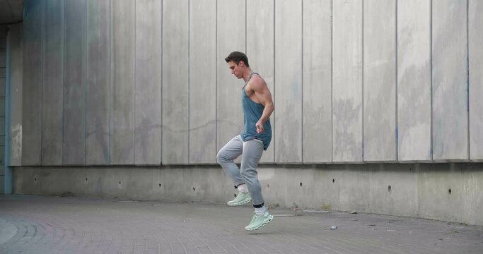 Athletic shirtless man training jump exercise on skipping rope on workout. Sporty man jumping with jumping rope. Young man training cardio exercises