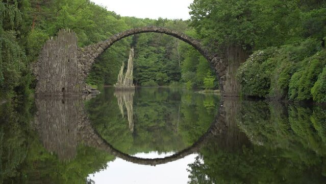 Reflection of arched Devil's Bridge in lake creates perfect circle, Gablenz