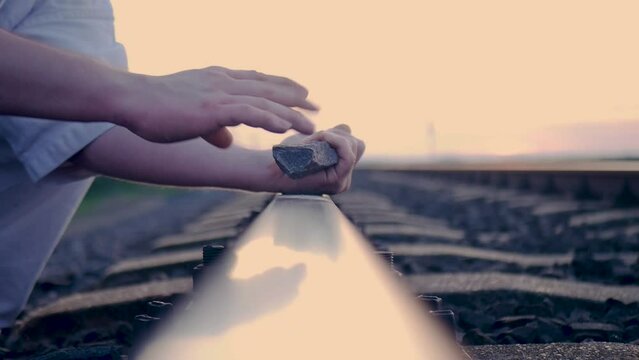 Close-up shot of a karate fighter breaking a stone on the train rail in the sunset, in slow motion. 60 fps.